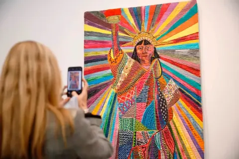 A woman photographs a vibrant quilt depicting the Statue of Liberty, a powerful piece by Asian American artists celebrating diversity.