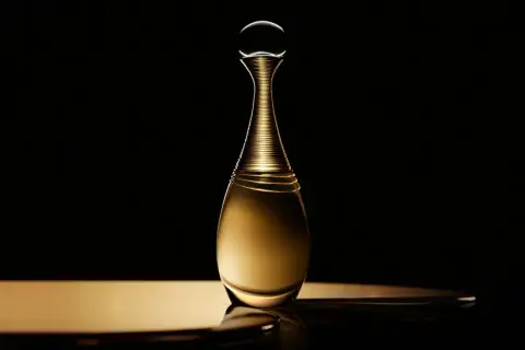 Złota butelka perfum Dior J'adore Infinissime na czarnym tle, emanująca luksusem i elegancją.
