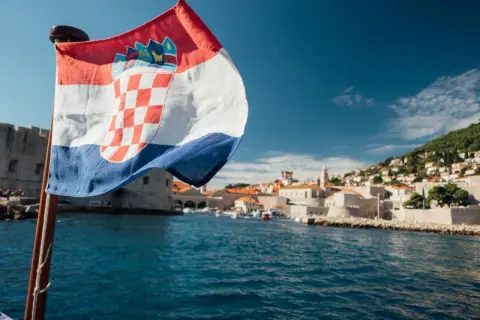 Chorwacka flaga na tle Dubrownika. Planujesz podróż? Sprawdź, co zabrać do Chorwacji jadąc samochodem.