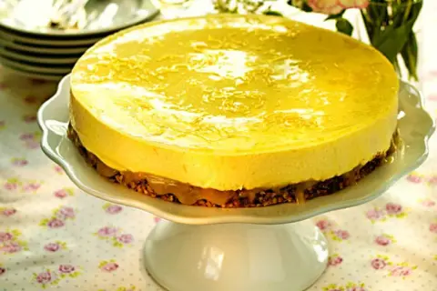 En härlig citronmousse till tårta, med en krispig botten och glansig topping, serveras på ett vackert tårtfat.