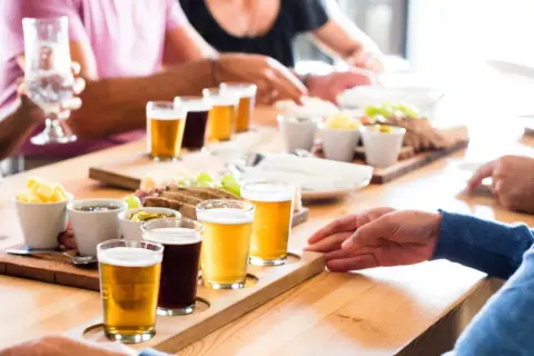 Un gruppo di persone partecipa a un corso degustazione birra, assaggiando diverse varietà accompagnate da stuzzichini.