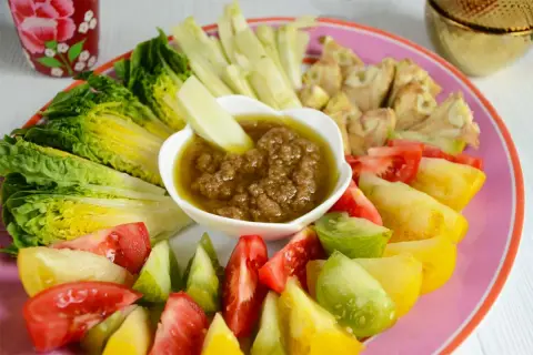 Assiette colorée de légumes frais (laitue, tomates variées, céleri) autour d'un bol de bagna cauda.