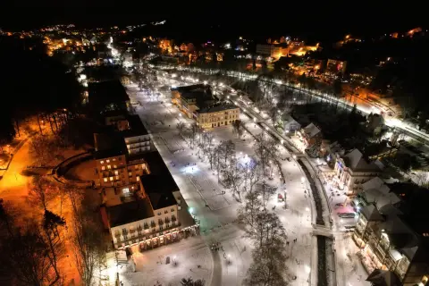 Krynica-Zdrój atrakcje wieczorem: ośnieżony deptak, iluminowane budynki i spacerujący ludzie tworzą magiczny zimowy krajobraz.