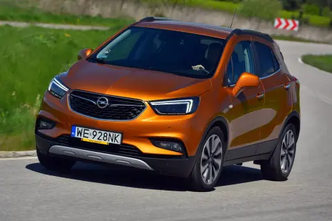 Pomarańczowy Opel Mokka 2015 na zakręcie drogi.