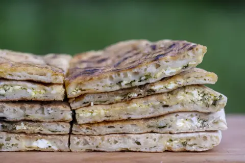 Pile de pains plats au fromage et aux herbes, rappelant l'origine du cheese naan.
