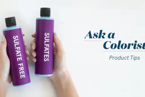 Manos sostienen dos botellas moradas: una dice "SULFATE FREE" y la otra "SULFATES". Aprende cómo saber si un champú tiene sulfatos.