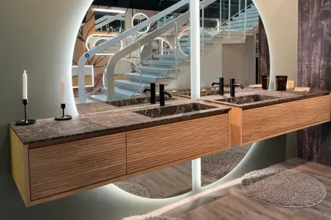 Une belle idée salle de bain marbre avec des meubles en bois et un grand miroir circulaire.