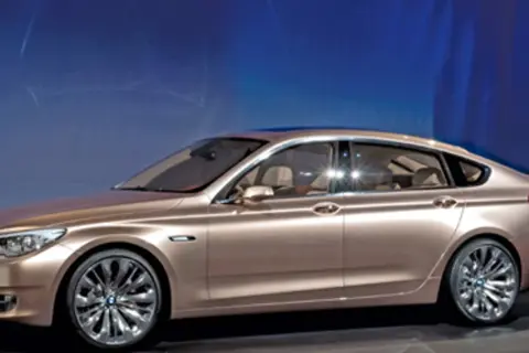 Eleganckie, złociste bmw 5gt z chromowanymi felgami prezentuje się imponująco na tle niebieskiego, świetlistego tła.