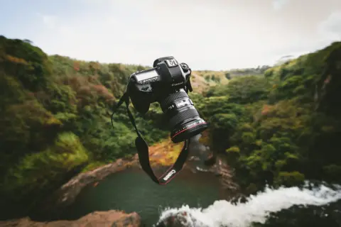 Un appareil photo bridge ou reflex flotte au-dessus d'une cascade luxuriante, prêt à capturer la beauté sauvage.