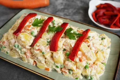 Spanischer Kartoffelsalat mit Thunfisch und Mayonnaise, garniert mit Paprika und Petersilie. Ein köstlicher Genuss!