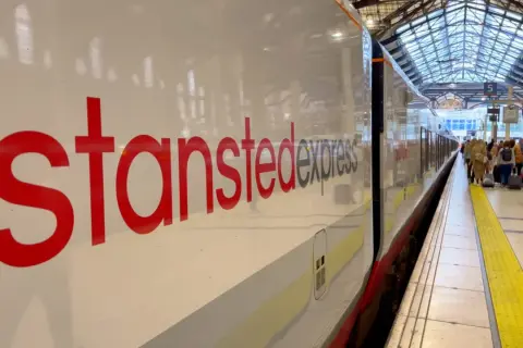 Stansted Express to Londyn – najtańszy sposób na podróż z lotniska. Pociąg czeka na pasażerów z bagażami.