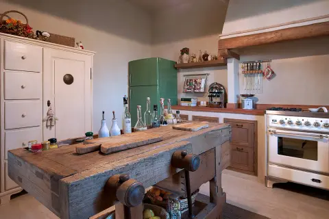 Un vecchio banco da falegname diventa un'isola cucina rustica, con taglieri e bottiglie d'olio.