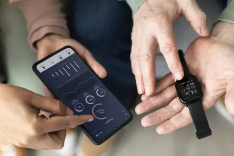 Dwie osoby analizują dane z zegarka Amazfit na smartfonie. Amazfit to firma znana z inteligentnych urządzeń do śledzenia aktywności.