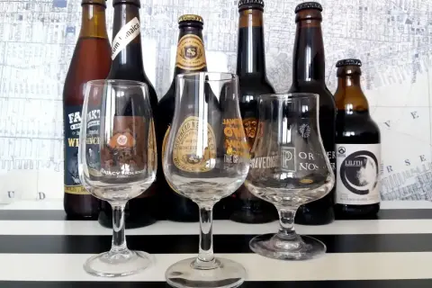 Kolekcja mocne piwo w butelkach i kieliszkach. Widać etykiety z nazwami jak "Lilith", "Gravedigger", "Fak't".