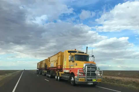 Żółty road train pędzi przez pustkowie. Zastanawiasz się, ile zarabia kierowca tira?