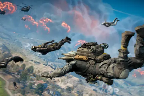 Żołnierze skaczą ze spadochronami nad płonącym polem bitwy. To intensywny battlefield battle royale.