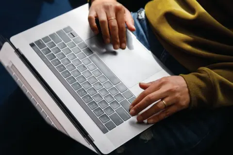 Person arbetar på laptop, kanske bokför bokföring för avdrag enskild firma.