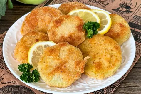 Knusprige Kohlrabi-Schnitzel auf einem Teller mit Zitronenscheiben und Petersilie garniert. Ein köstliches vegetarisches Gericht.