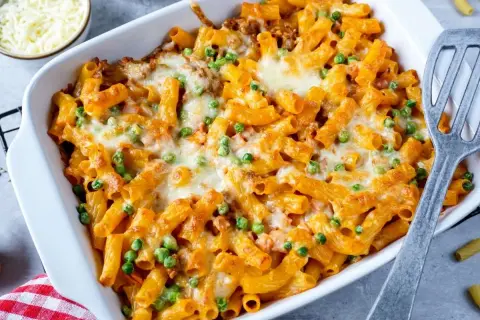 Herzhaftes Rigatoni al Forno mit Erbsen und geschmolzenem Käse in einer Auflaufform, bereit zum Servieren.