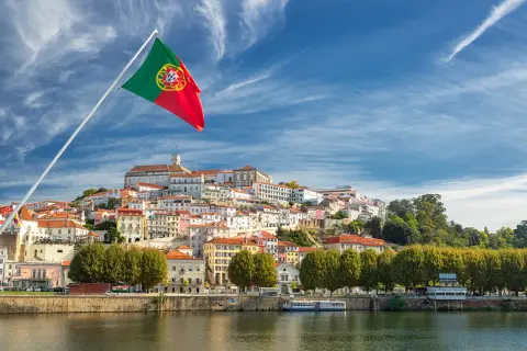 Flaga Portugalii nad rzeką. Miasto na wzgórzu, idealne na wakacje, gdzie portugalia temperatura wody zachęca do kąpieli.