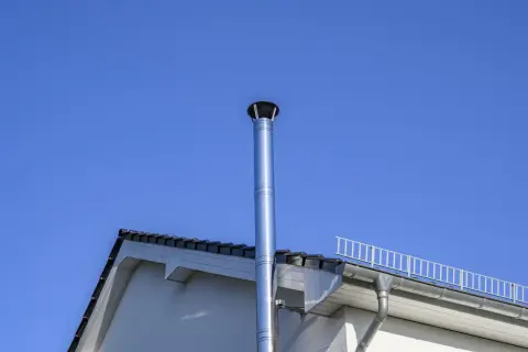 Edler Edelstahl-Schornstein mit 150 mm Durchmesser für einen Pelletofen, ragt vor blauem Himmel empor.