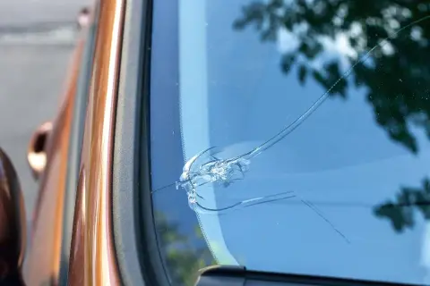 En spricka i vindrutan på en orange bil. Det ser ut som att det är dags att laga stenskottet innan det blir värre.