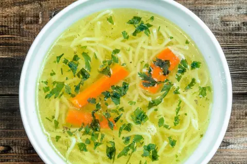 Aromaticzny rosół z makaronem, marchewką i natką pietruszki. Czy rosół ma białko? Tak, dzięki mięsu, z którego jest gotowany, dostarcza cennego białka.