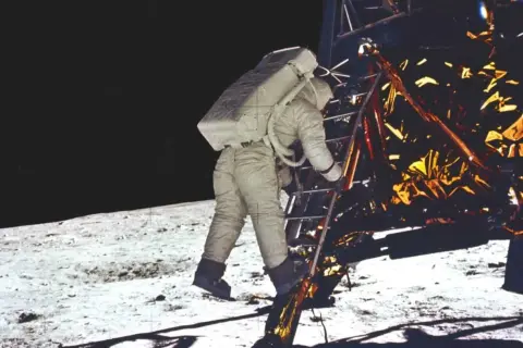 Astronaut schodzi po drabinie modułu księżycowego, rozpoczynając historyczne lądowanie na księżycu.