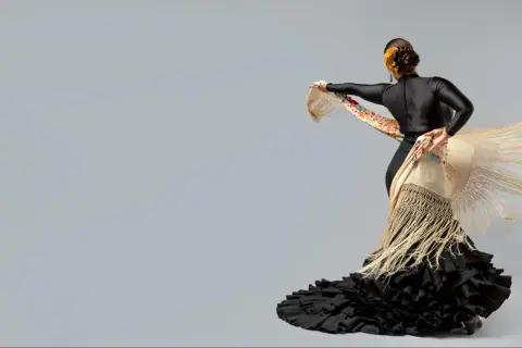 Bailarina con traje de flamenca negro y mantón bordado. Un ejemplo de cómo planchar un traje de flamenca para que luzca impecable.