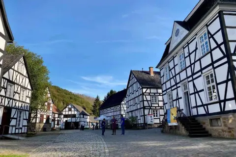 Fachwerkhäuser in einem Freilichtmuseum, das zeigt, was ist ein Freilichtmuseum. Besucher schlendern über Kopfsteinpflaster.