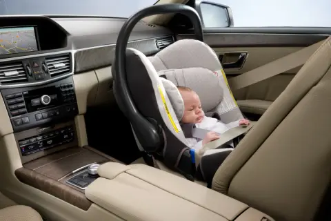 Un bébé dort paisiblement dans un siège auto, prêt pour le voyage. La **taille pour monter devant en voiture** est parfaite pour ce siège.