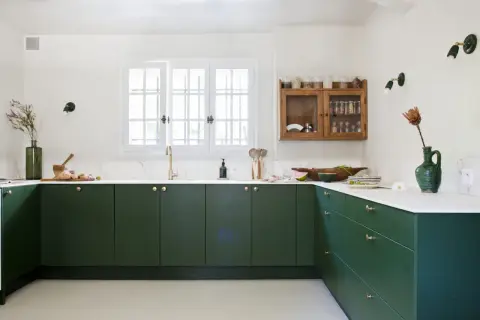 Cuisine moderne avec des armoires vert forêt profond. La couleur mur cuisine est blanc cassé, contrastant avec les meubles sombres.