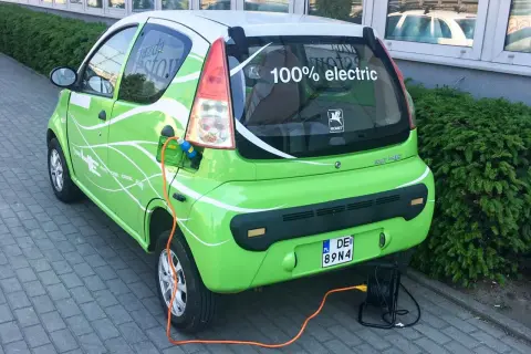 Zielony elektryczny samochód ROMET HE z napisem "100% electric" jest ładowany. To część programu "Mój Elektryk".