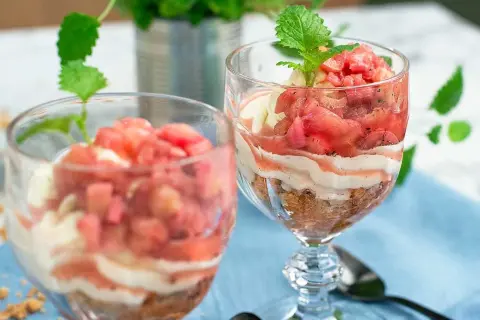 Två glas med en härlig dessert av rabarber i glas, varvad med krämig vanilj och smulad kaka. En frisk och somrig smakupplevelse.
