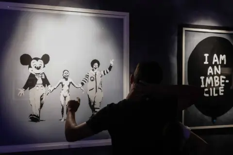 Wystawa "Banksy zdemaskowany" prezentuje dzieła artysty, w tym obraz z postaciami Myszki Miki i Ronalda McDonalda trzymających się za ręce.