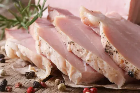 Kawałki super delikatnego i soczystego schabu gotowanego, przyprawione pieprzem, z gałązką rozmarynu.
