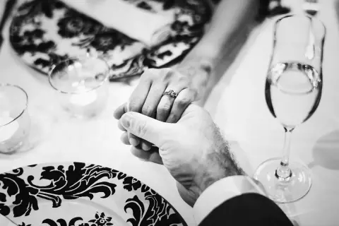 Mani intrecciate, un anello che simboleggia 40 anni di matrimonio smeraldo o rubino. Brindisi con champagne per celebrare un amore duraturo.