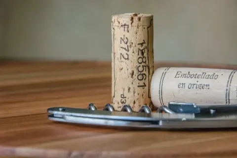 Korki do wina i korkociąg na drewnianym stole. Czas na wino bez korka!