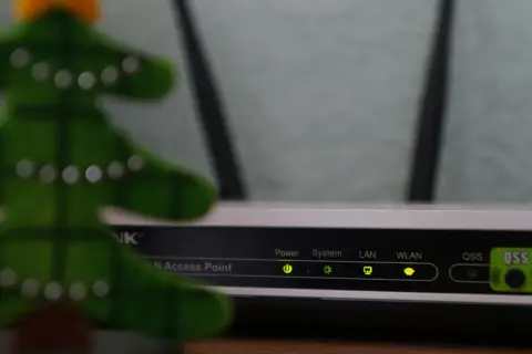 Świąteczna choinka obok routera, gotowa do konfiguracji sieci LAN. Wskaźniki Power, System, LAN, WLAN świecą się zielono.