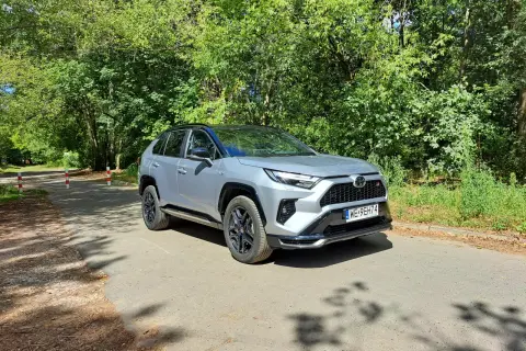 Srebrny Toyota RAV4 Hybrid na leśnej drodze. Zastanawiasz się nad jego spalaniem? Ten SUV oferuje świetne osiągi i niskie zużycie paliwa.