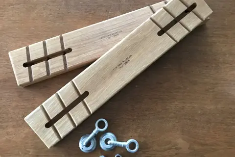 Two wooden batter boards with slots and notches, alongside eye bolts and nuts, ready for a construction project.