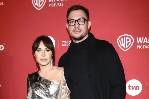 Blanka Lipińska z partnerem na czerwonym tle z logo Warner Bros. Pictures.