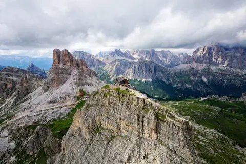 Un refuge de montagne perché sur un pic rocheux, au cœur des Dolomites en Italie. Un paysage spectaculaire de montagnes escarpées et de vallées verdoyantes.