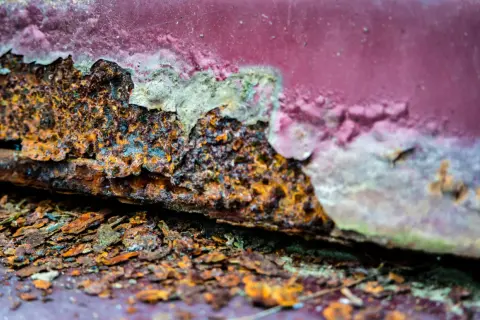 Stark verrostete Kante mit abgeblätterter roter Farbe. Ein Beispiel für entrosten mit Essig und Backpulver.