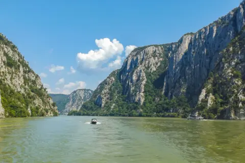 Rejs przez skalne wąwozy, gdzie rzeka tworzy naturalną, żelazną bramę. Dwie łodzie płyną po zielonej wodzie.