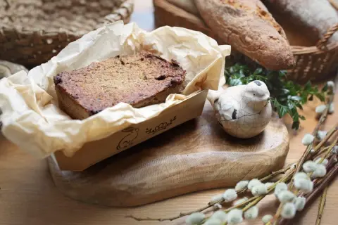 Pyszny pasztet z królika w papierowej foremce z zajączkiem, obok ceramiczny ptaszek i chleb.