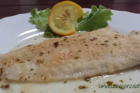 Sogliola al forno con panatura croccante, guarnita con una fetta di limone e insalata fresca. Un piatto leggero e gustoso.