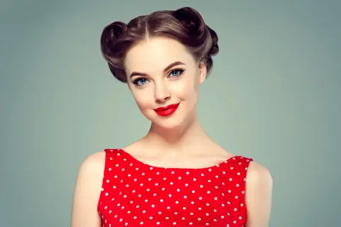 Kobieta w czerwonej sukience w grochy z perfekcyjnymi fryzurami retro i mocnym makijażem.