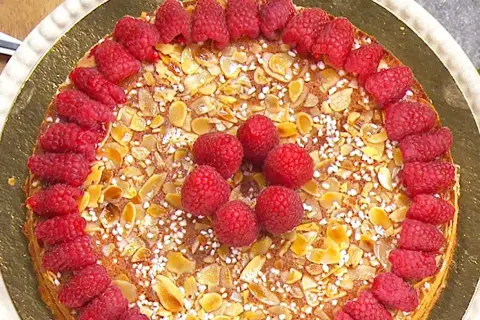 En vacker mandelkaka med citron, toppad med färska hallon och mandelflagor. En härlig sommartårta!