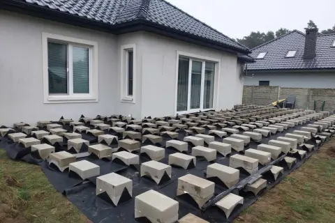 Budowa tarasu z deski kompozytowej na bloczkach betonowych. Podkład z agrowłókniny chroni przed chwastami.